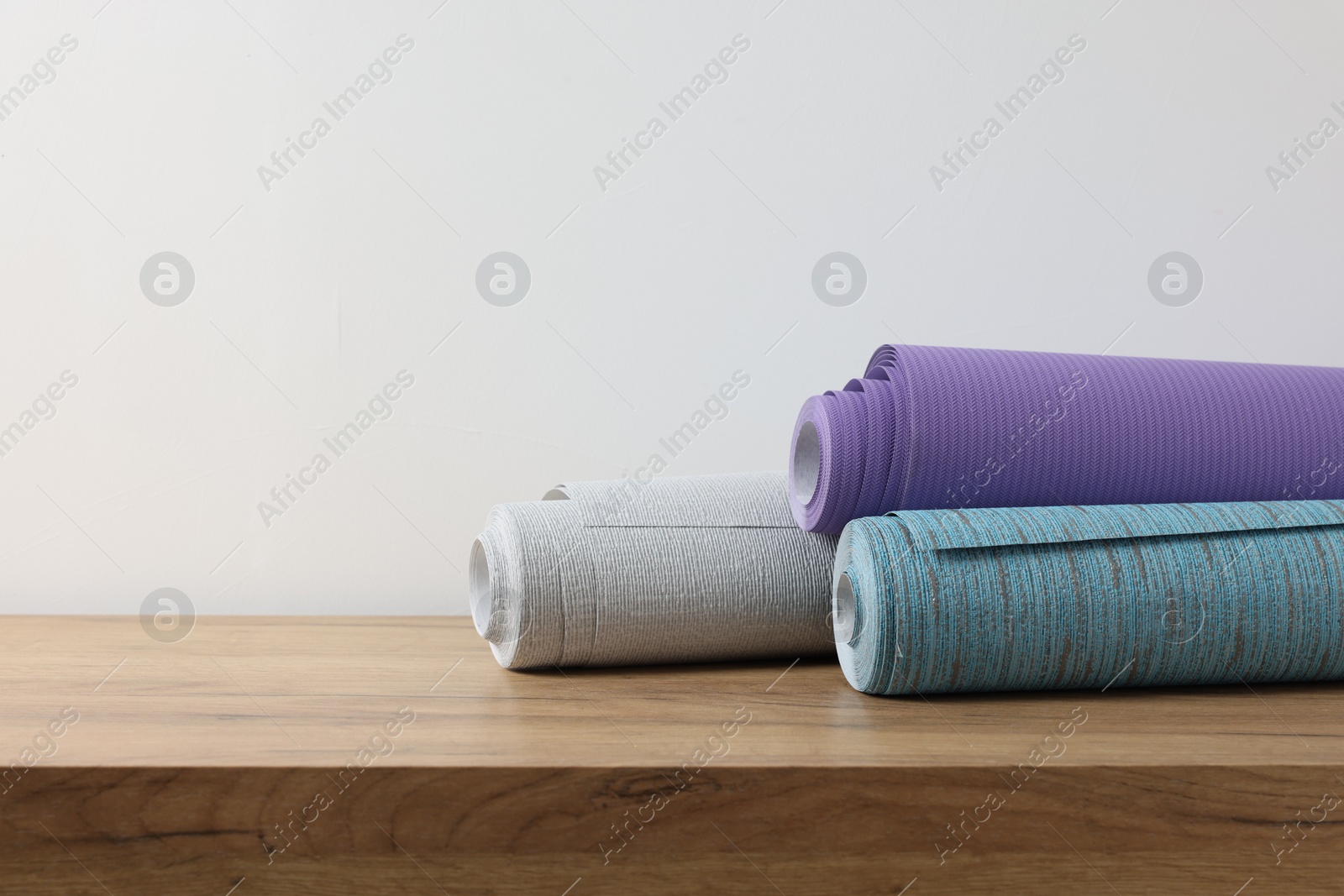 Photo of Three different wallpaper rolls on wooden table, space for text