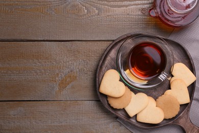 Photo of Heart shaped cookies with tea served on wooden table, flat lay. Space for text