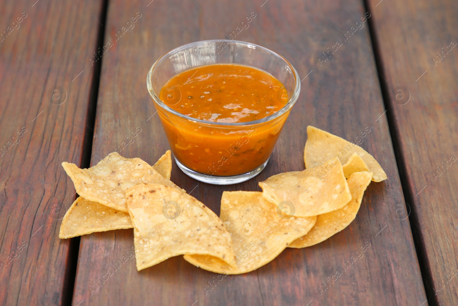 Photo of Tasty salsa sauce and Mexican nacho chips on wooden table, closeup
