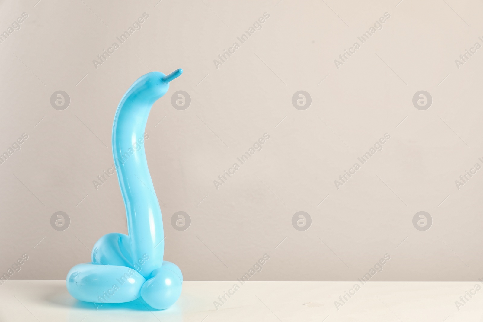 Photo of Snake figure made of modelling balloon on table against color background. Space for text