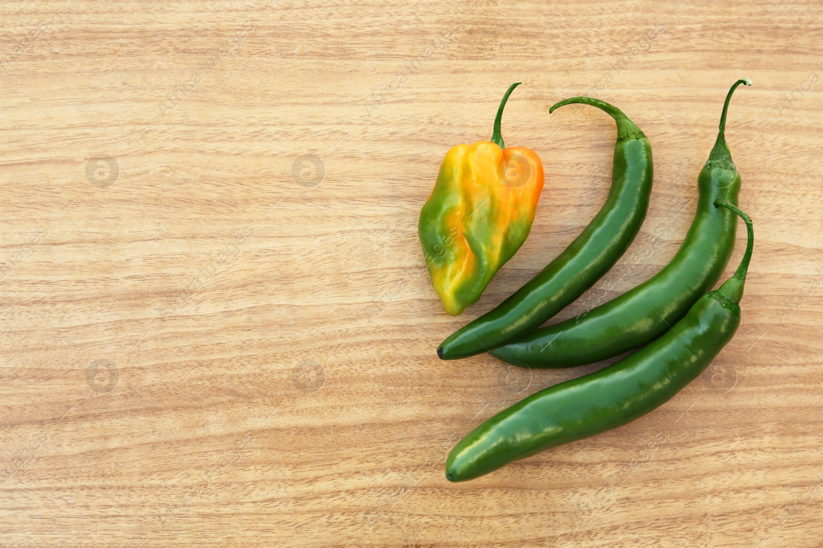 Photo of Different fresh ripe peppers on wooden table, flat lay. Space for text