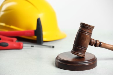 Photo of Construction and land law concepts. Gavel, hard hat, hammer and screwdrivers on white table, closeup with space for text