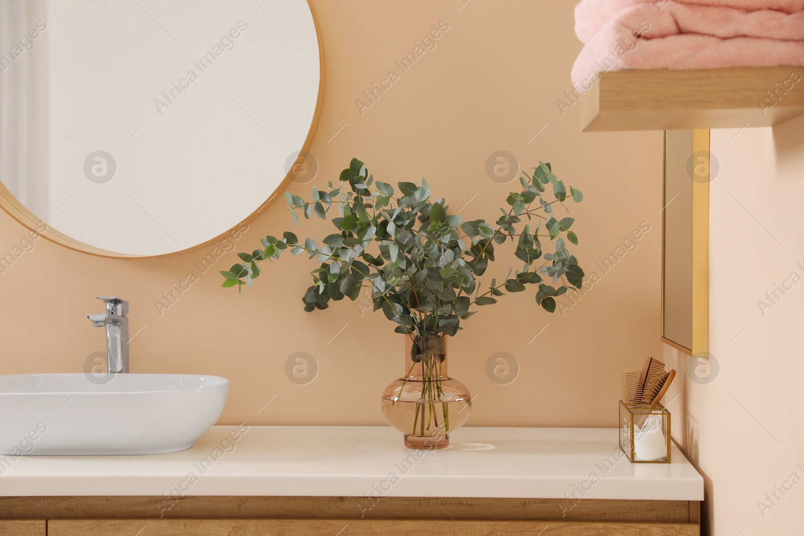 Photo of Stylish mirror, eucalyptus branches and vessel sink in modern bathroom. Interior design