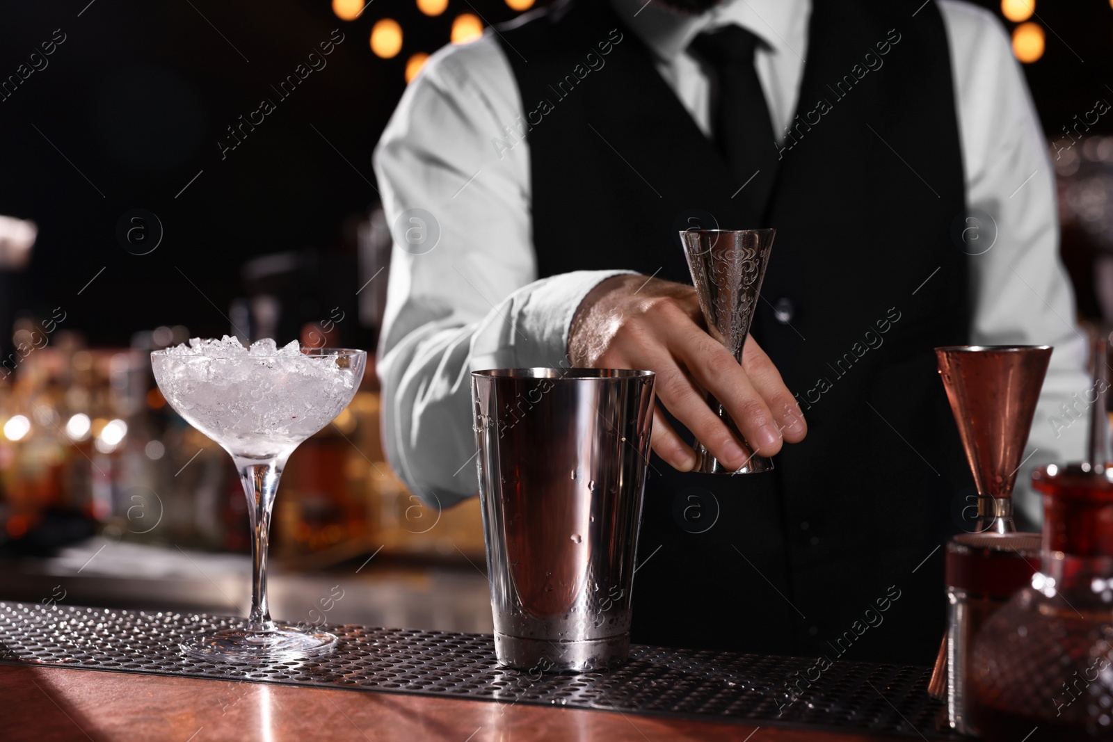 Photo of Bartender preparing fresh alcoholic cocktail in martini glass at bar counter, closeup