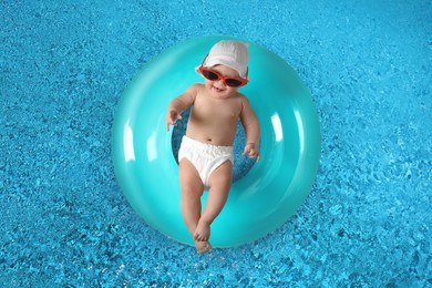 Cute little baby with inflatable ring in swimming pool, top view