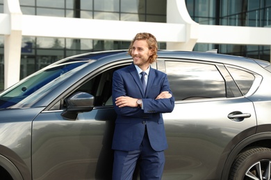 Photo of Attractive young man near luxury car outdoors