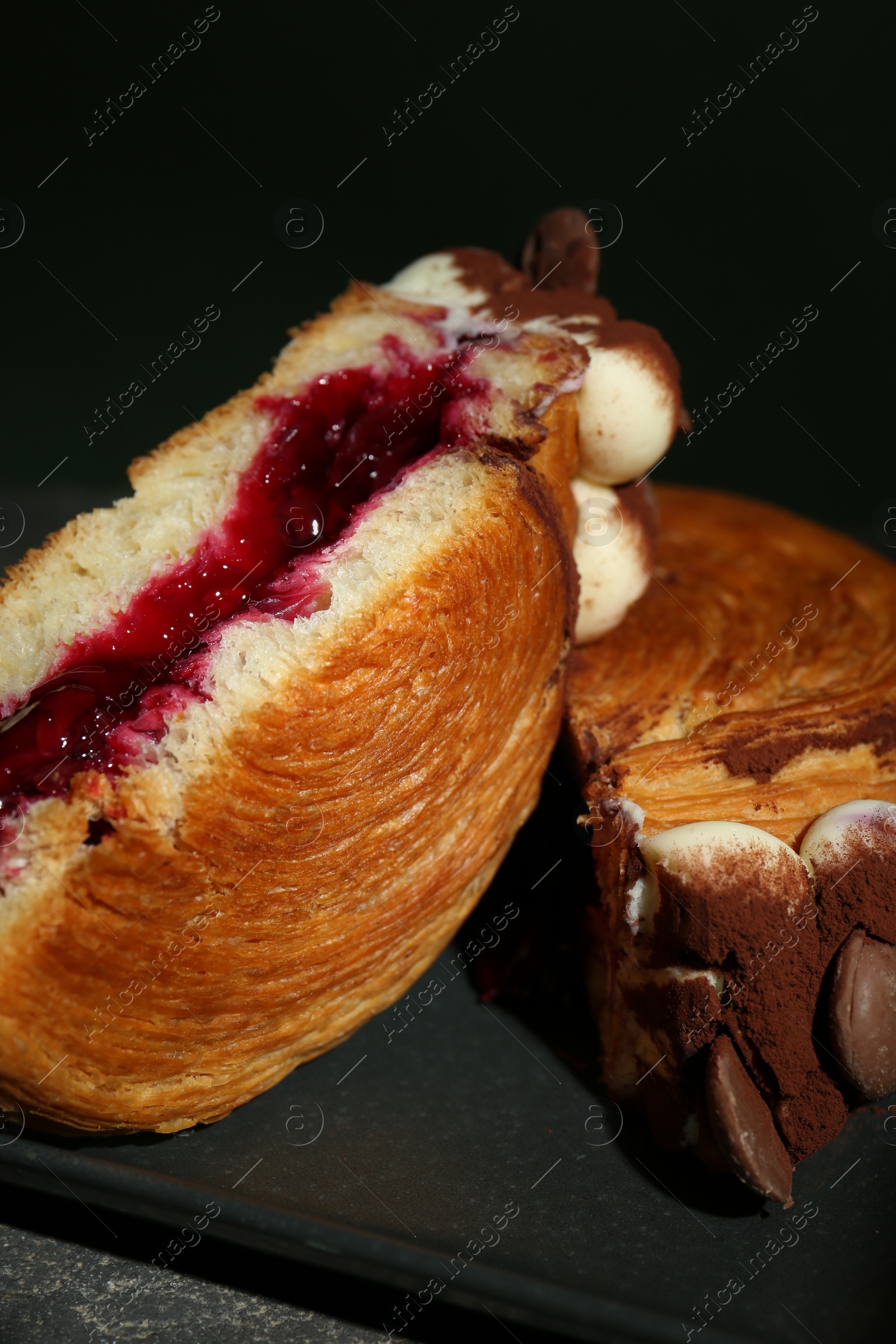 Photo of Round croissant with jam, cream and chocolate chips on table, closeup. Tasty puff pastry