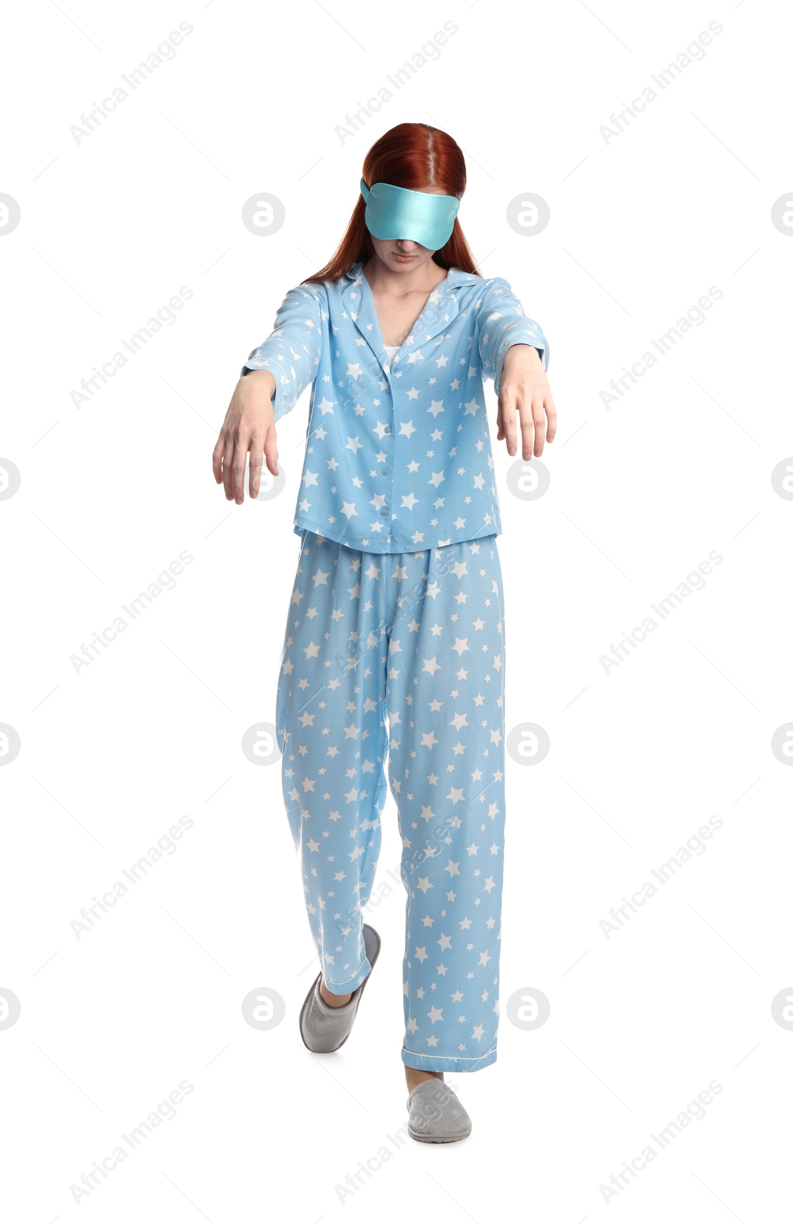 Photo of Young woman wearing pajamas, mask and slippers in sleepwalking state on white background