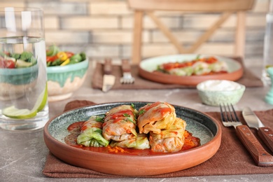 Photo of Plate with stuffed cabbage leaves in tomato sauce on table