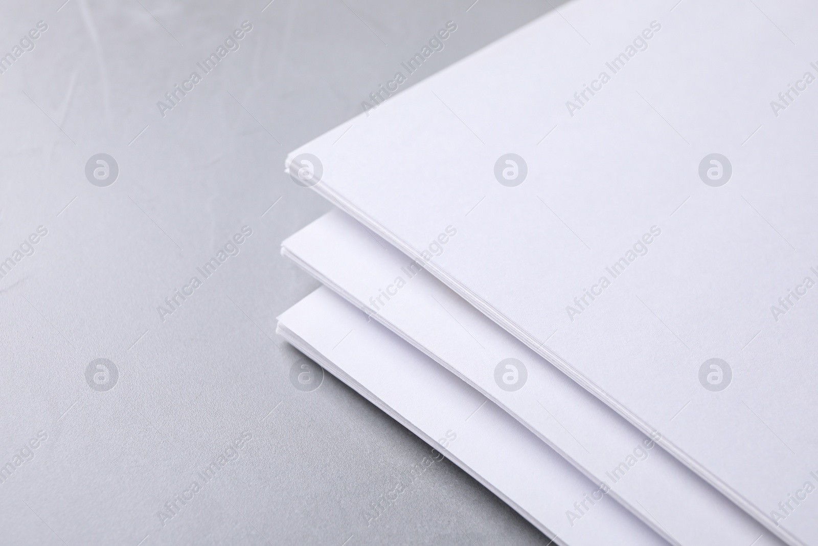 Photo of Blank paper sheets on light grey stone background, closeup. Mock up for design