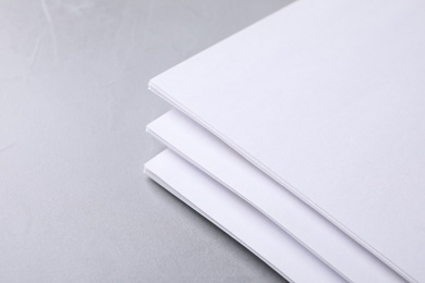 Photo of Blank paper sheets on light grey stone background, closeup. Mock up for design