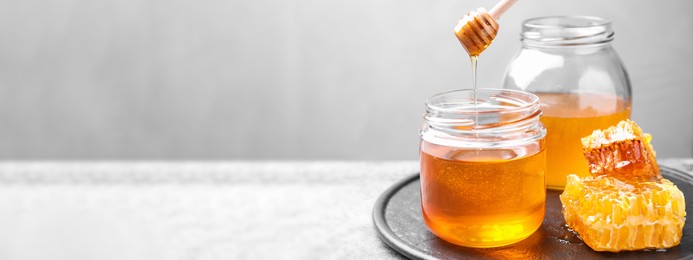 Image of Tasty fresh aromatic honey on grey table, space for text. Banner design