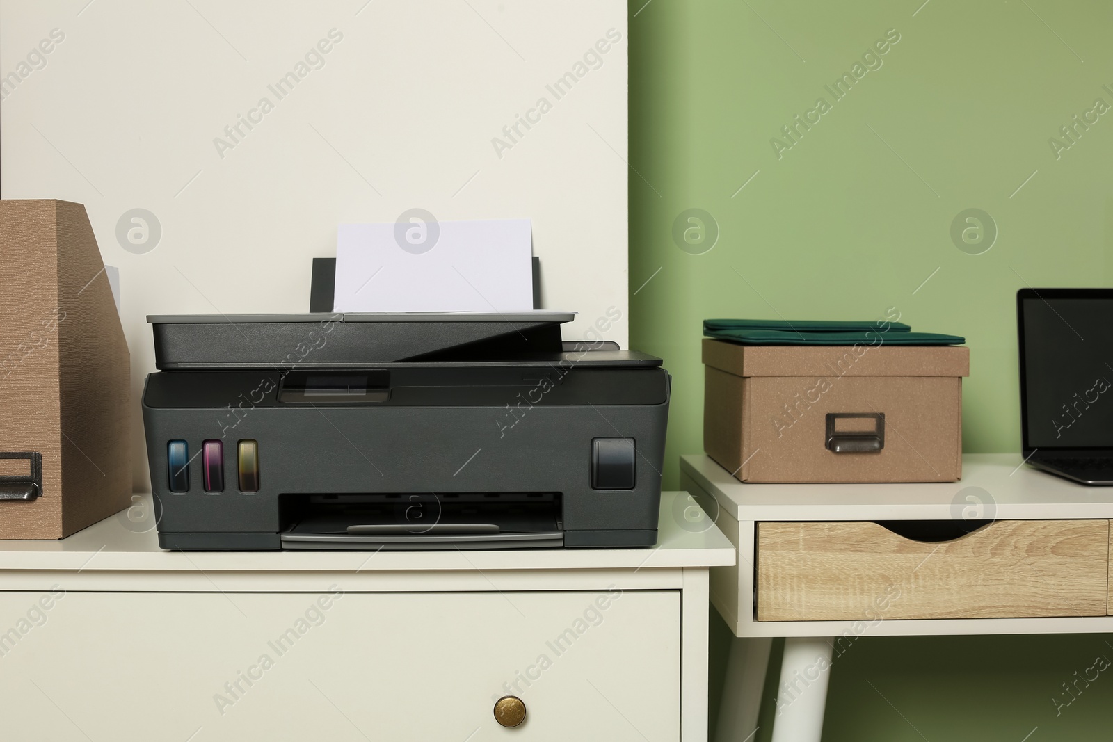 Photo of Modern printer with paper on white chest of drawers near stylish workplace indoors