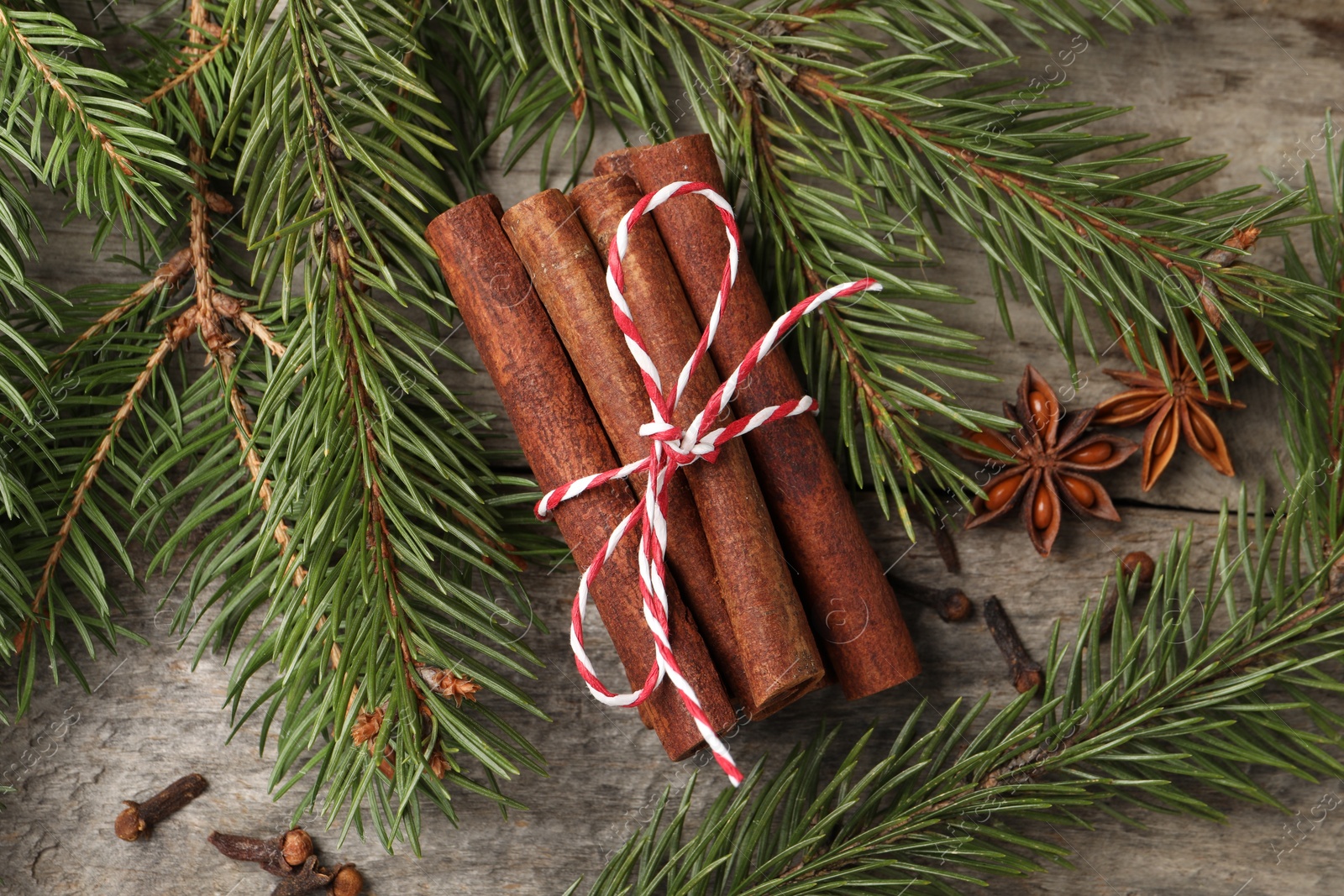 Photo of Different spices and fir branches on wooden table, flat lay