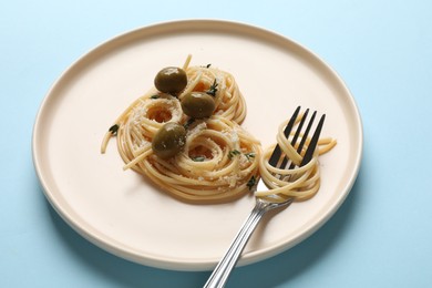 Photo of Heart made of tasty spaghetti, fork, olives and cheese on light blue background