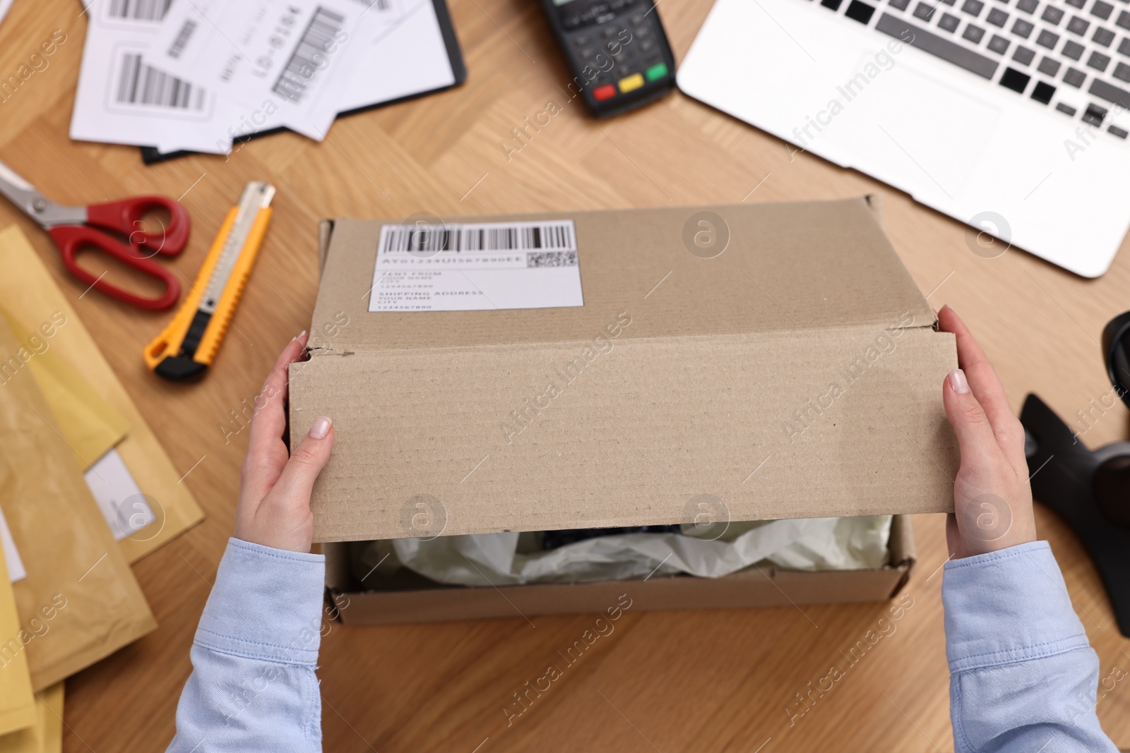 Photo of Post office worker packing parcel at wooden table, top view