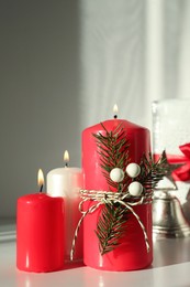 Photo of Burning candles with Christmas decor on white table