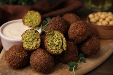 Photo of Delicious falafel balls and sauce on table, closeup