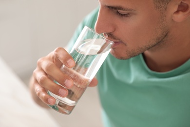 Photo of Man drinking pure water from glass indoors, closeup
