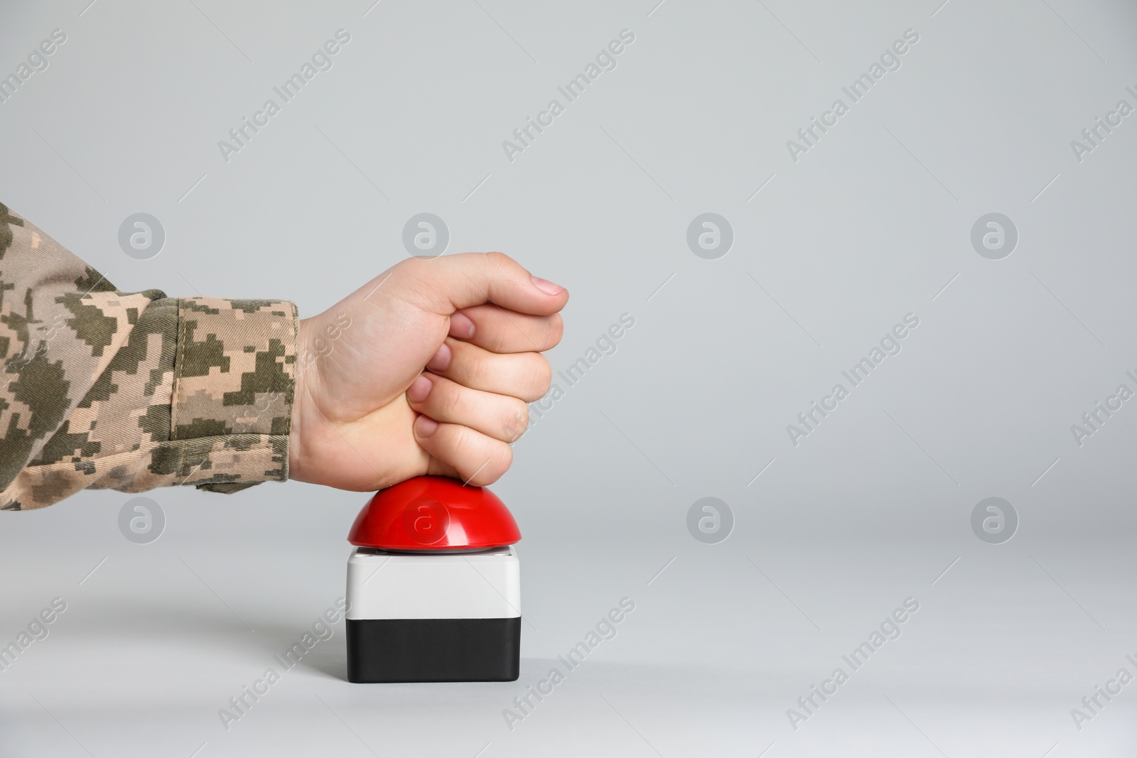 Photo of Serviceman pressing red button of nuclear weapon on light gray background, closeup with space for text. War concept
