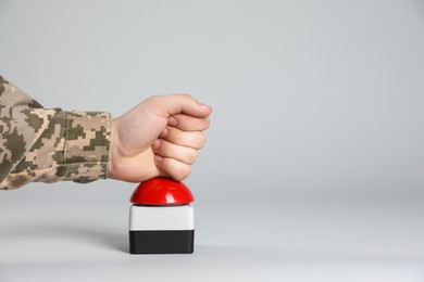 Photo of Serviceman pressing red button of nuclear weapon on light gray background, closeup with space for text. War concept