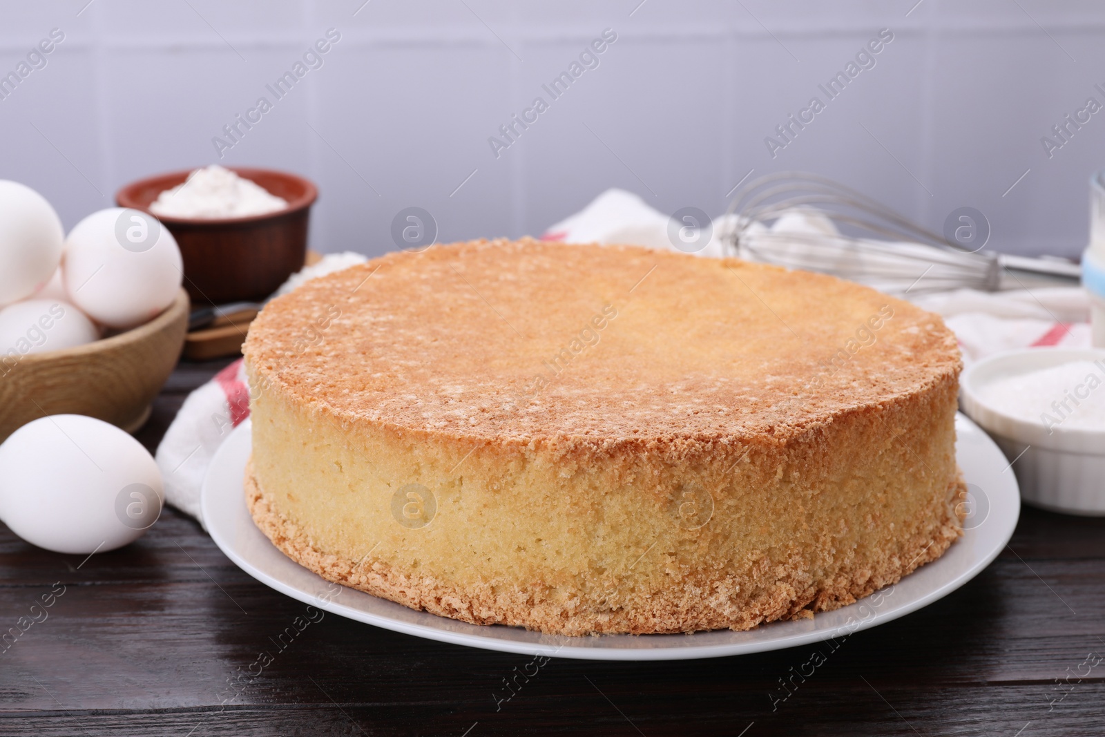 Photo of Plate with delicious sponge cake on dark wooden table, closeup