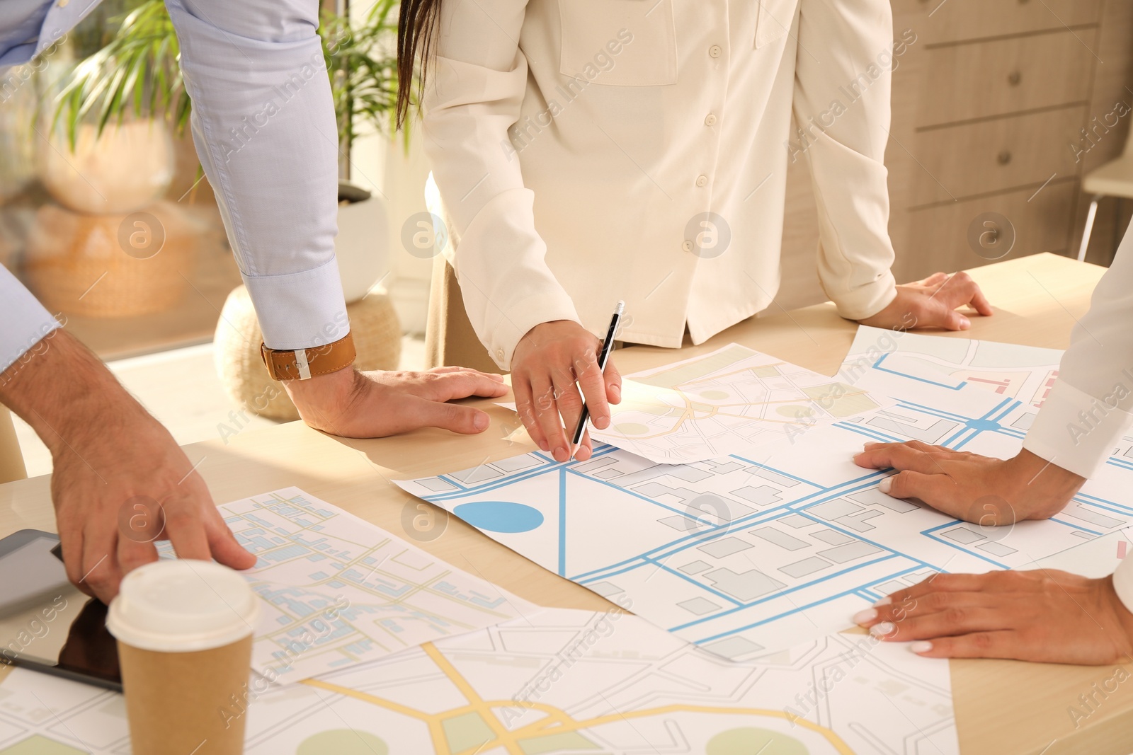 Photo of Professional cartographers working with cadastral map at table in office, closeup