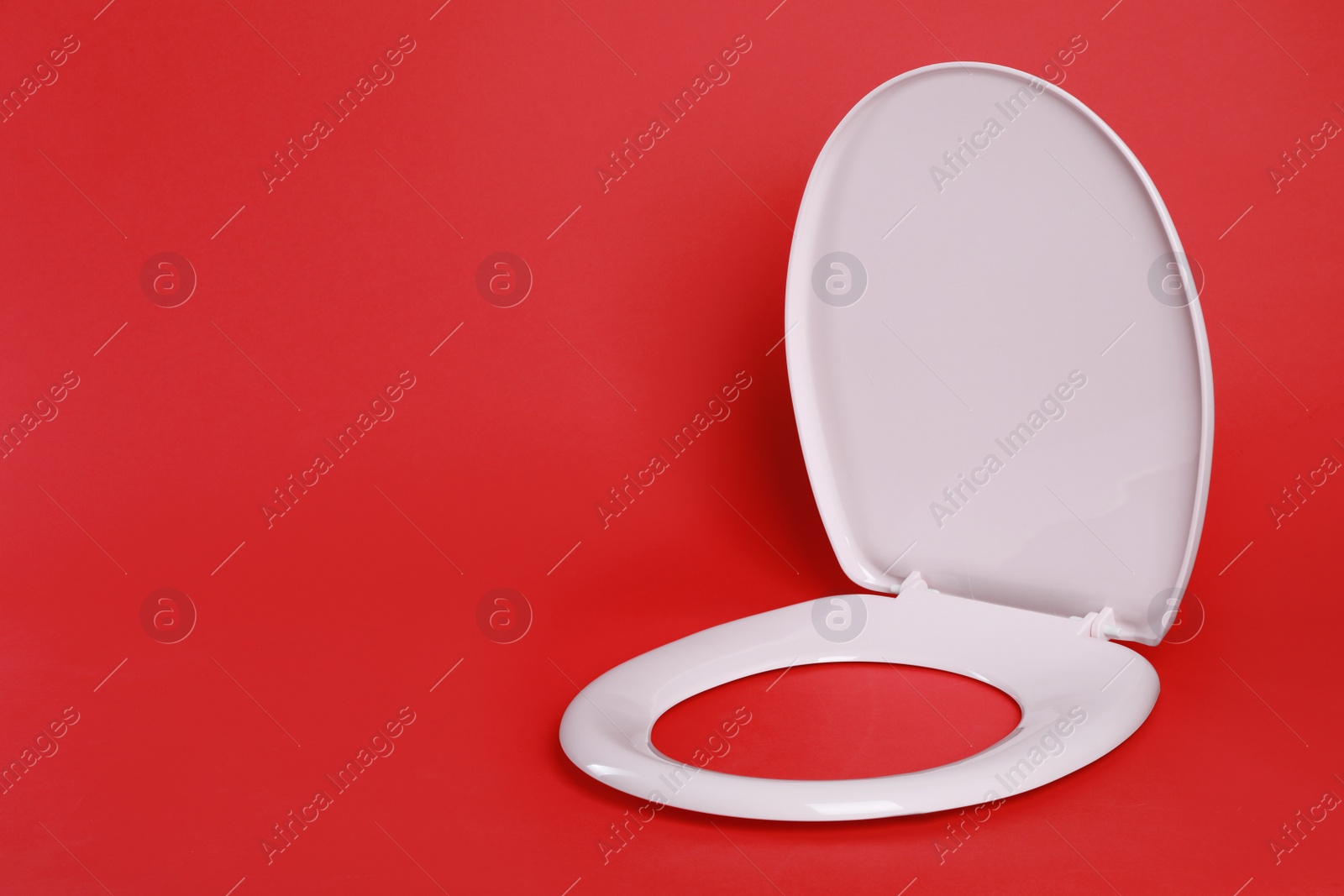 Photo of New pink plastic toilet seat on red background, space for text