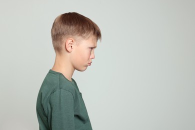 Photo of Upset boy on light grey background, space for text. Children's bullying