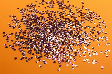Photo of Shiny bright violet glitter on orange background