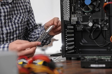Photo of Male technician repairing computer at table, closeup