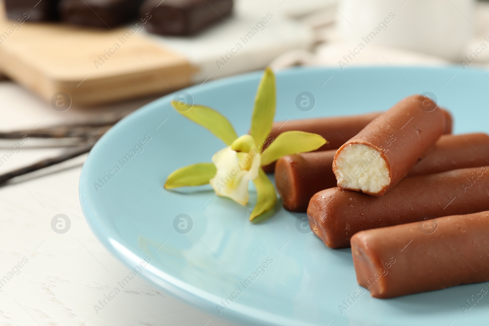 Photo of Glazed vanilla curd cheese bars served on white wooden table, closeup