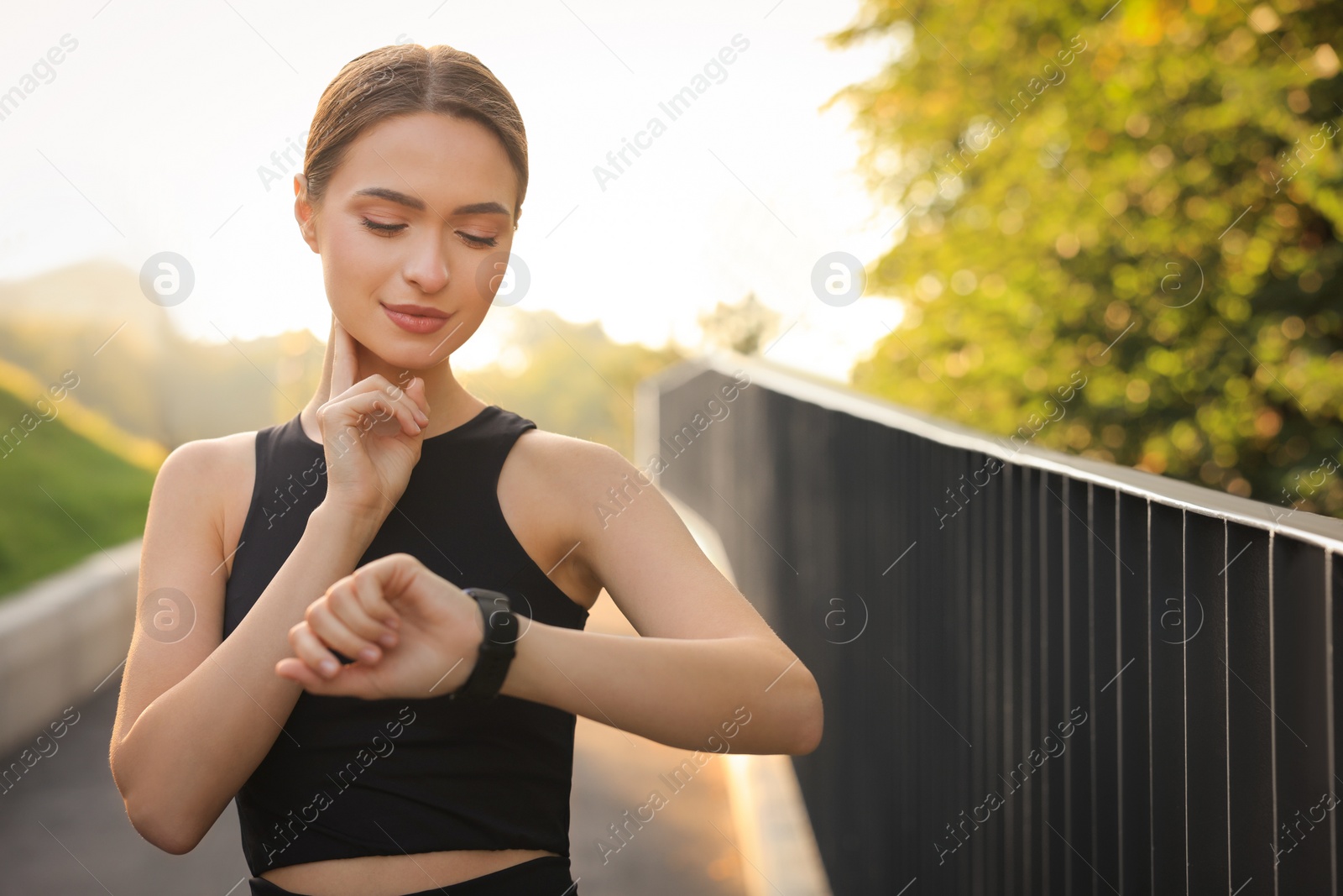 Photo of Attractive happy woman checking pulse after training in park. Space for text