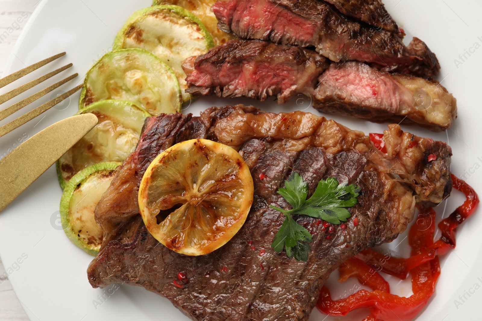 Photo of Delicious grilled beef steak and vegetables on plate, top view