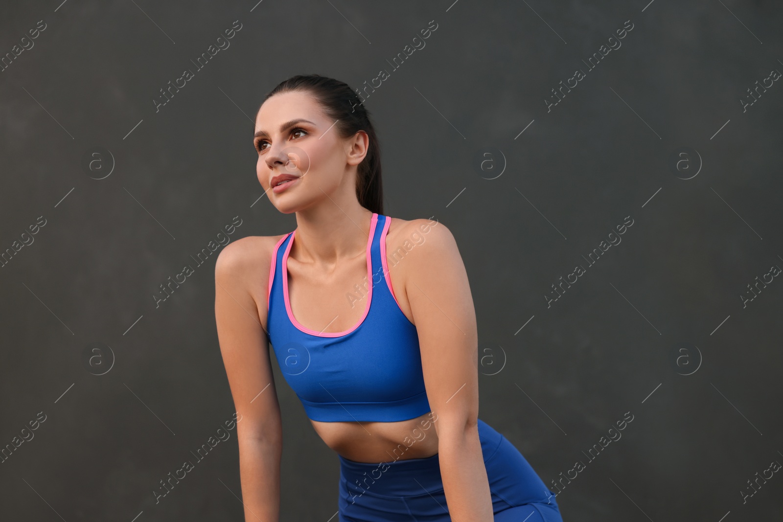 Photo of Beautiful woman in stylish sportswear near black wall. Space for text