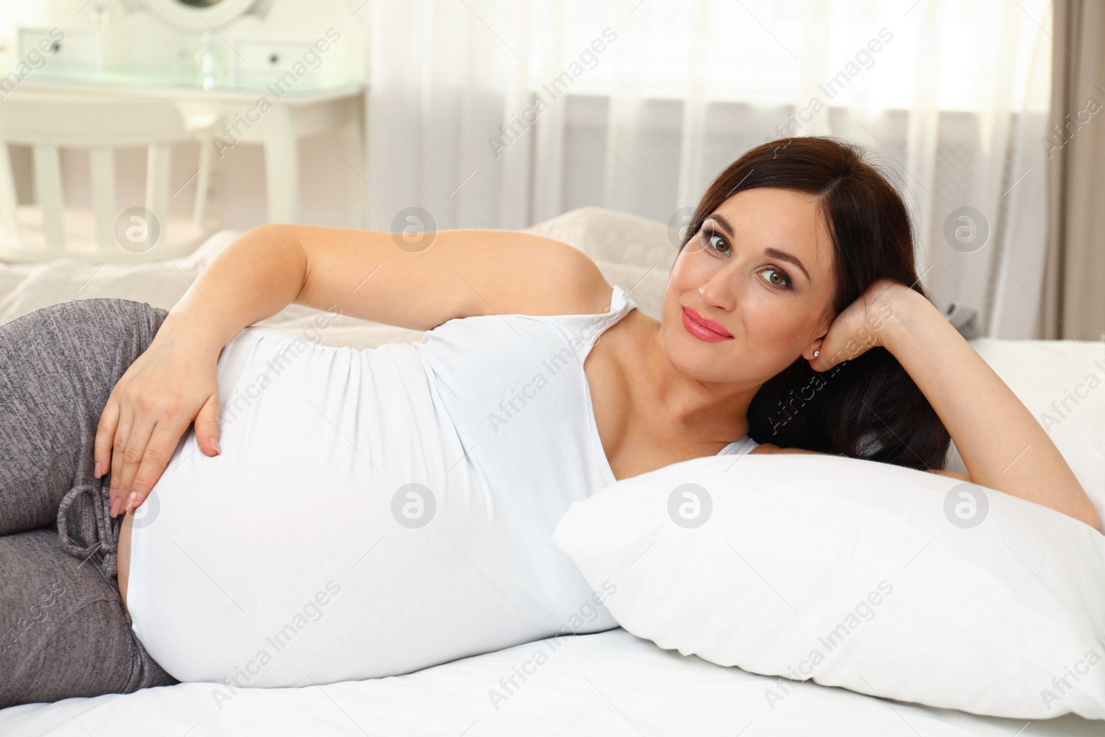 Photo of Beautiful pregnant woman lying on bed at home