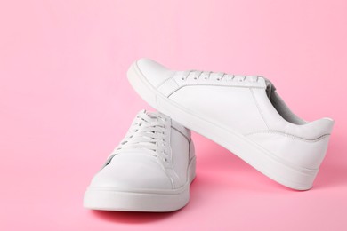 Photo of Pair of stylish white sneakers on pink background