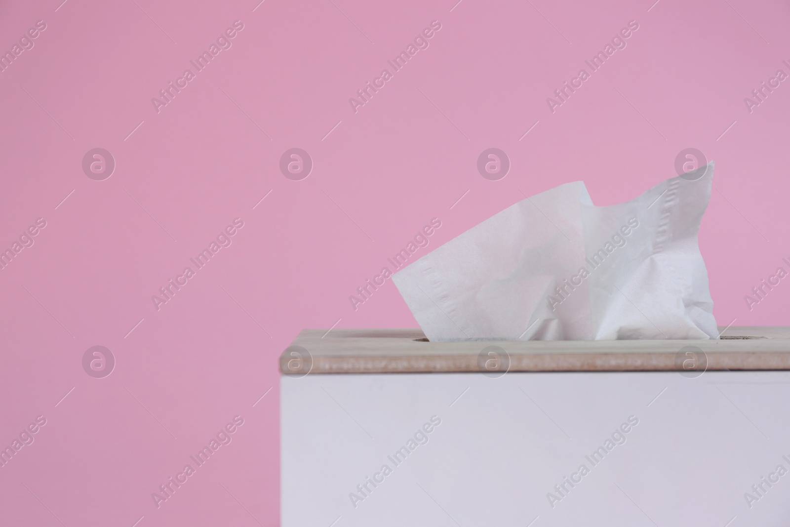 Photo of Holder with paper tissues on pink background, closeup. Space for text