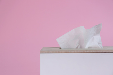 Photo of Holder with paper tissues on pink background, closeup. Space for text