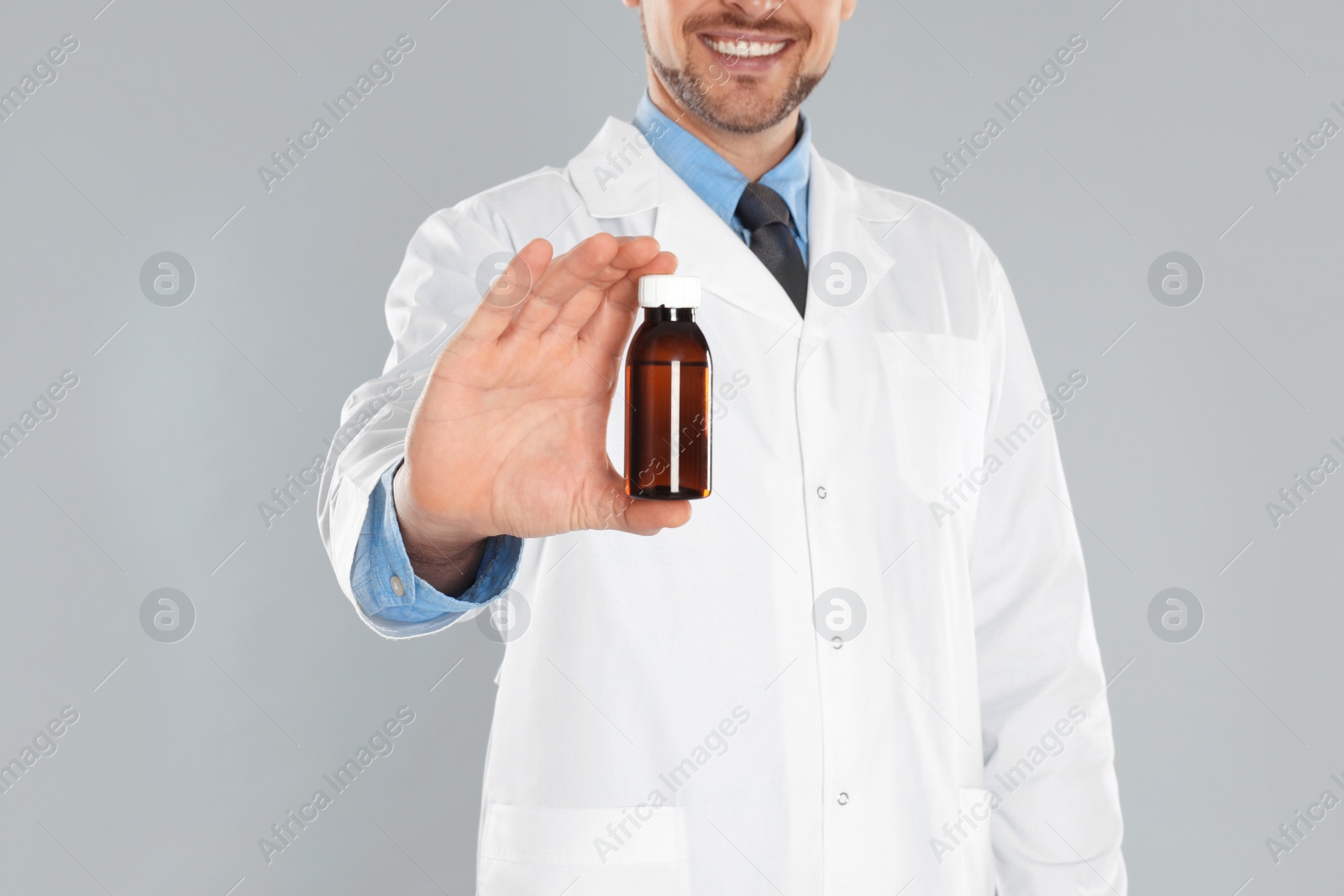 Photo of Professional pharmacist with syrup on light grey background, closeup