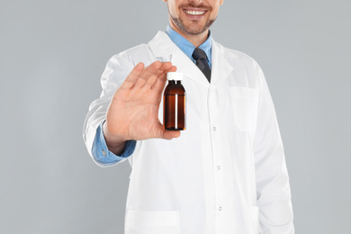 Photo of Professional pharmacist with syrup on light grey background, closeup
