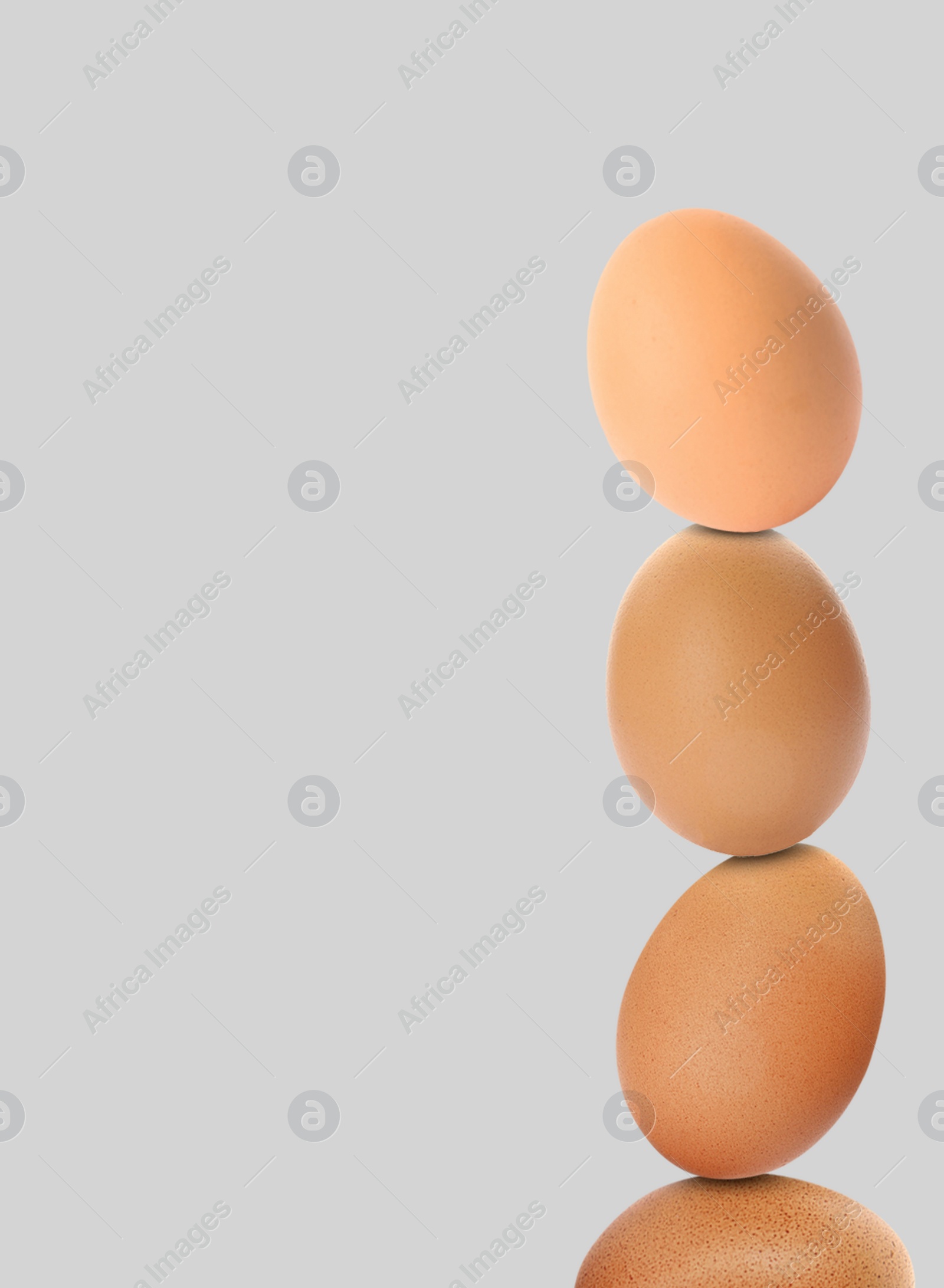 Image of Stacked fresh chicken eggs against light grey background. Space for text