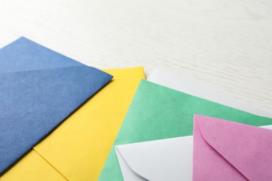 Photo of Colorful paper envelopes on white wooden background, closeup