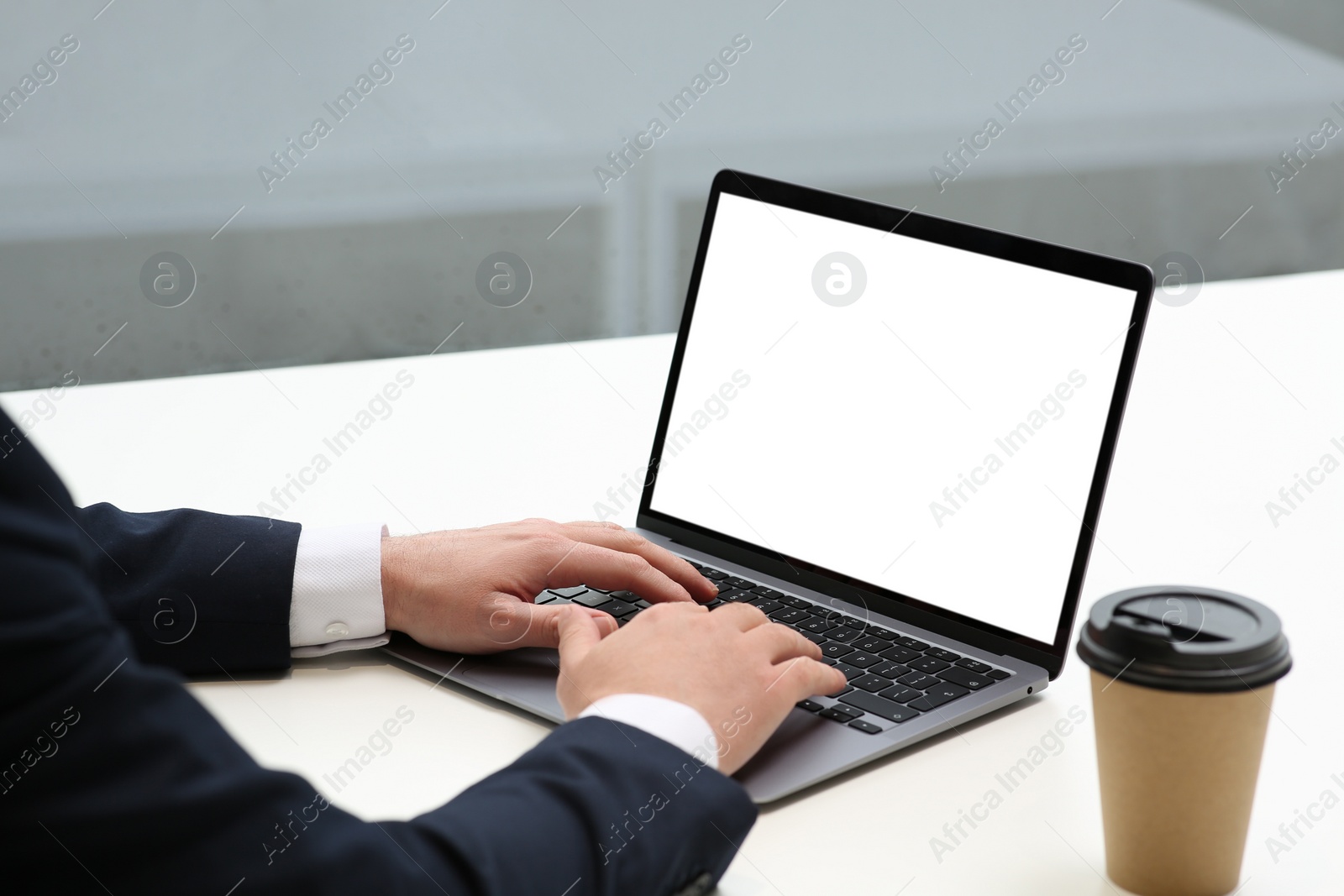 Photo of Man working on laptop at white desk in office, closeup