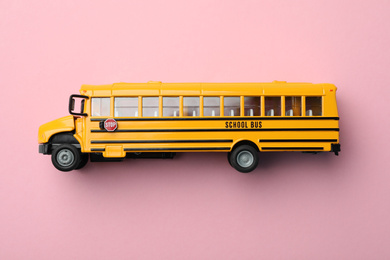Photo of Yellow school bus on pink background, top view. Transport for students