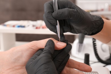 Photo of Professional manicurist working with client in salon, closeup