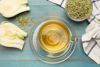 Photo of Aromatic fennel tea, seeds and fresh vegetable on light blue wooden table, flat lay