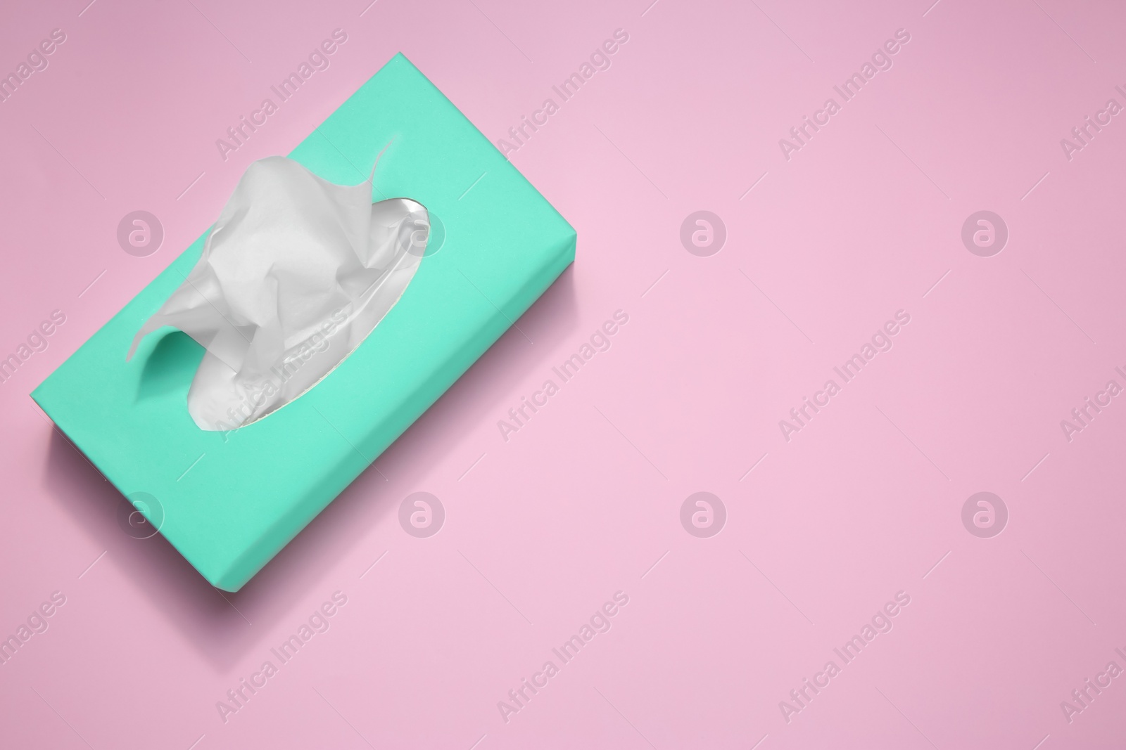 Photo of Box with paper tissues on pink background, top view. Space for text