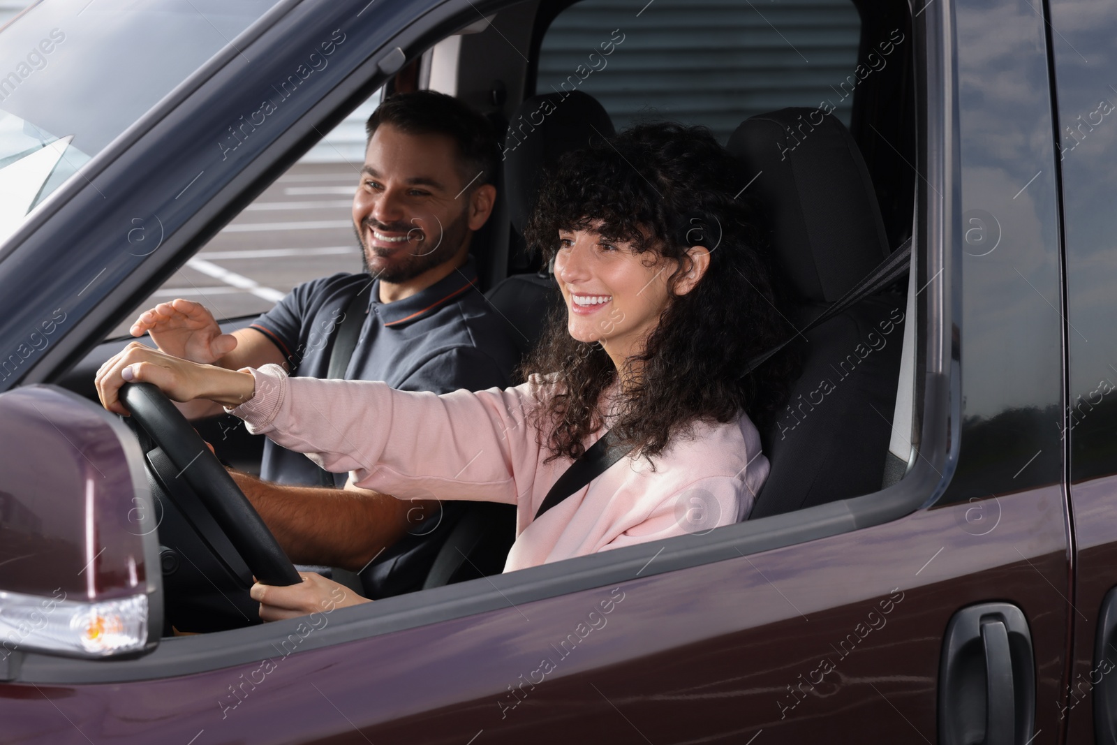 Photo of Driving school. Happy student during lesson with driving instructor in car