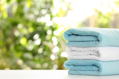 Photo of Stack of clean soft towels on table against blurred background. Space for text